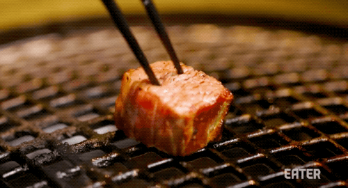 Graphic GIF of someone turning over a piece of meat using chopsticks over a Korean barbecue grill