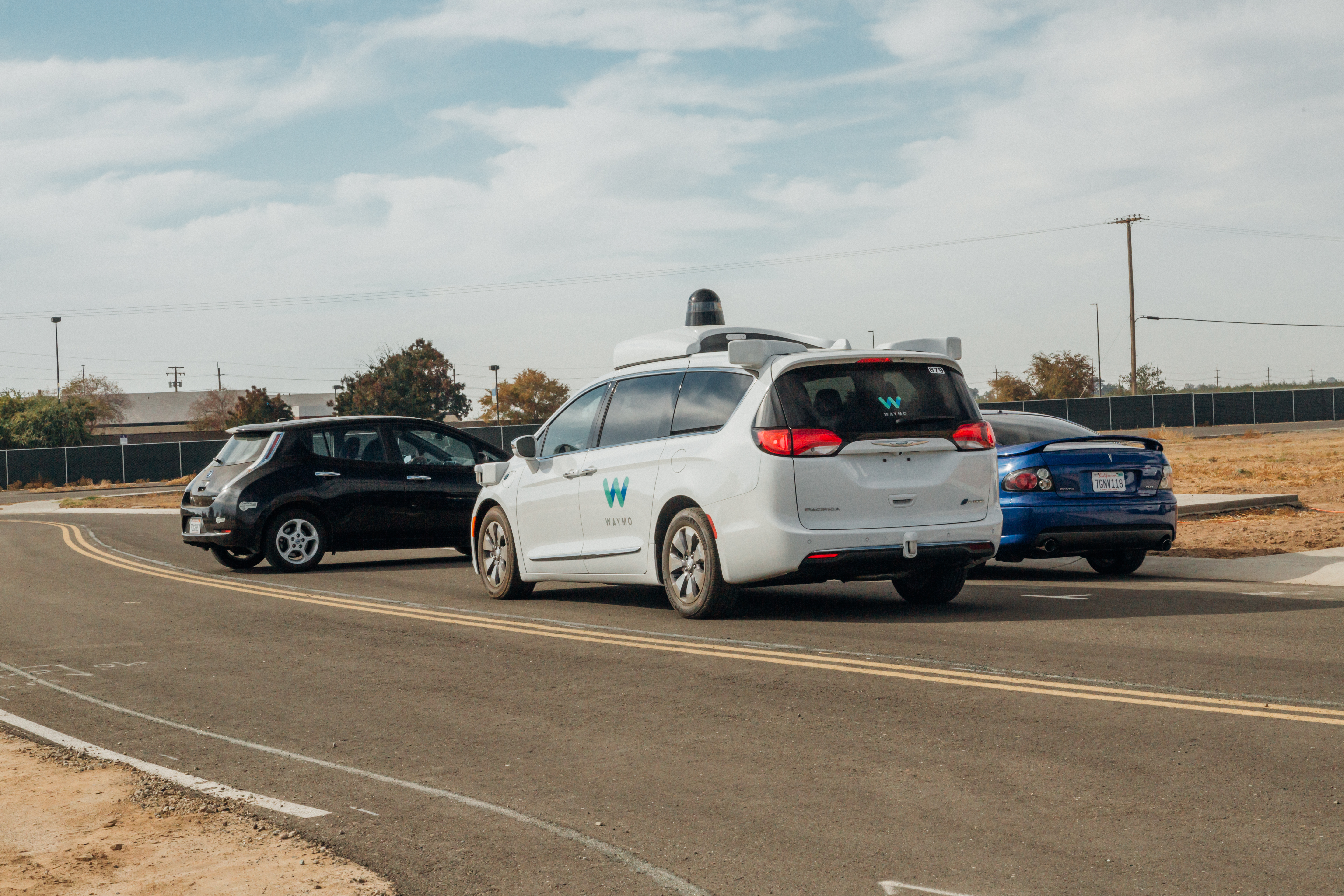 Waymo’s driverless minivan stops as a car pulls out of its parking spot onto the street. 