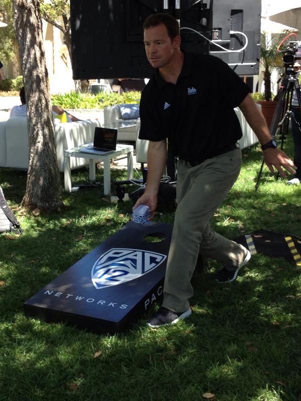 Coach Mora Playing a Game of Cornhole at Pac-12 Media Day 2