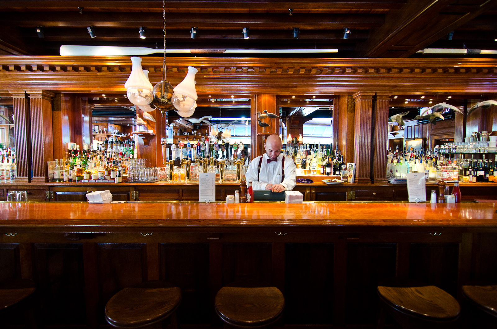 The wooden bar, with a bartender in suspenders