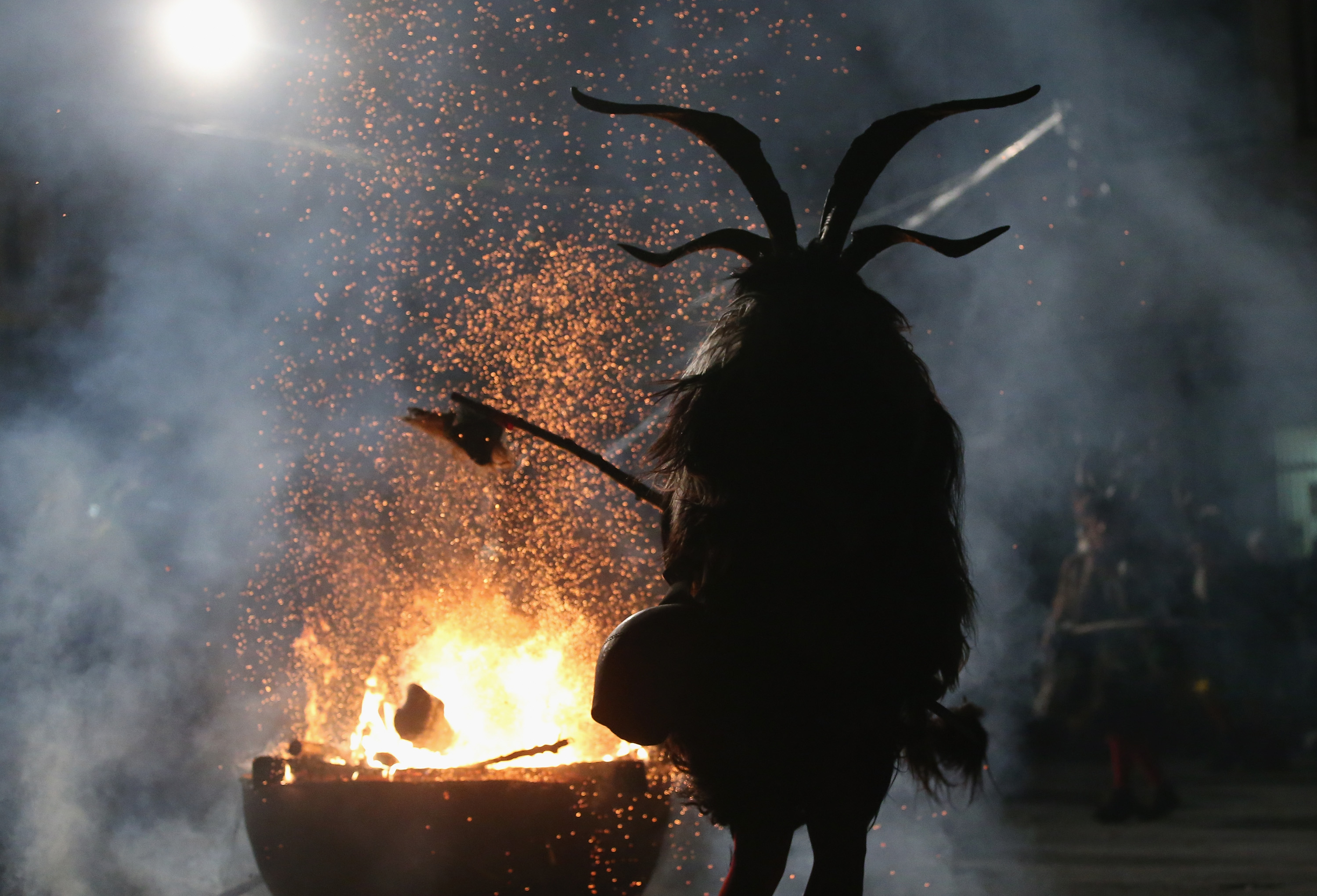 A member of the Haiminger Krampusgruppe dressed as the Krampus creature hits a fire to release sparks on the town square during their annual Krampus night in Tyrol on December 1, 2013, in Haiming, Austria.