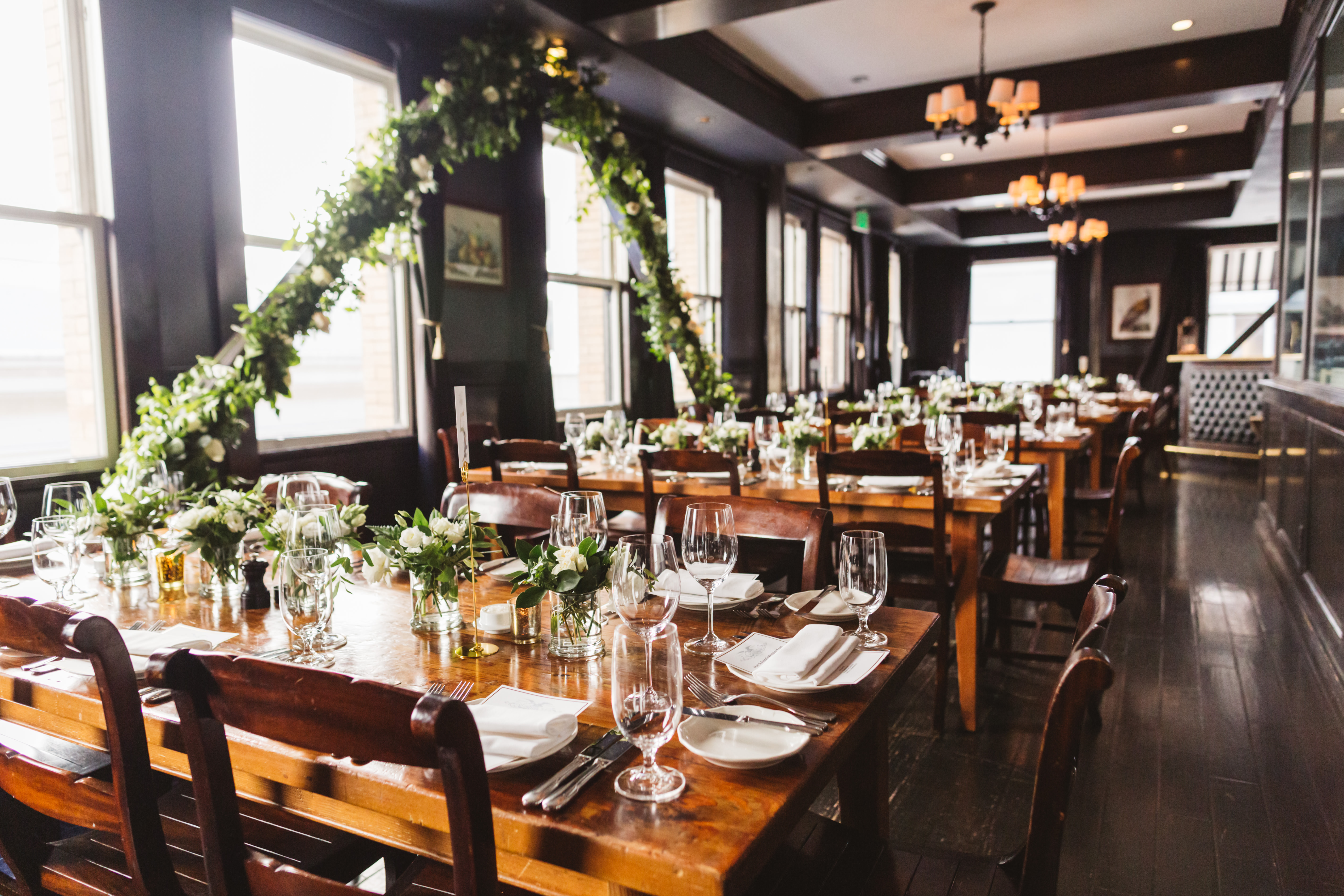 Rows of tables at Wayfare Tavern are decorated with place settings and white flowers for a wedding reception