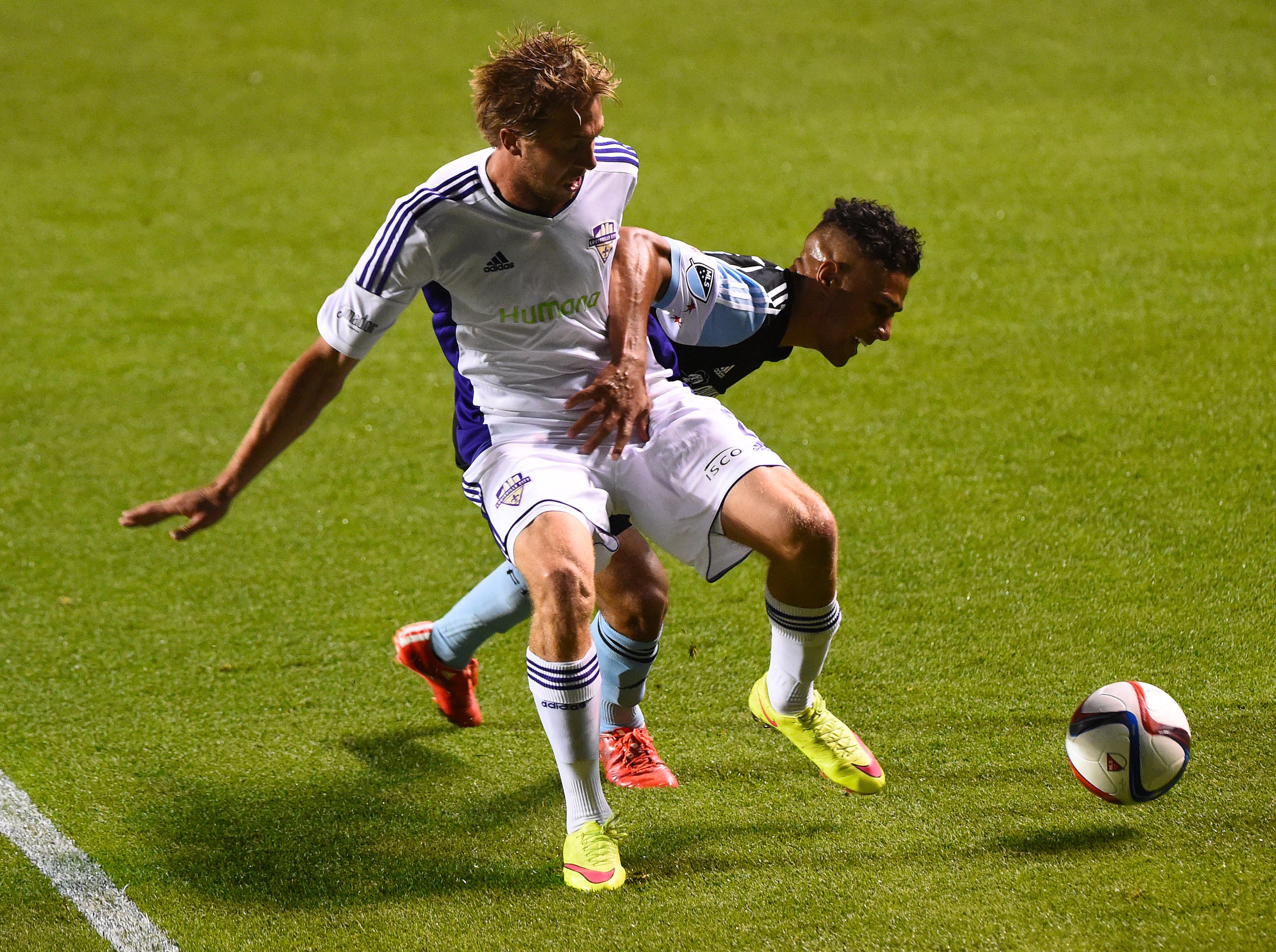 Louisville City right back Bryan Burke holds up a Chicago Fire player in a match from June.