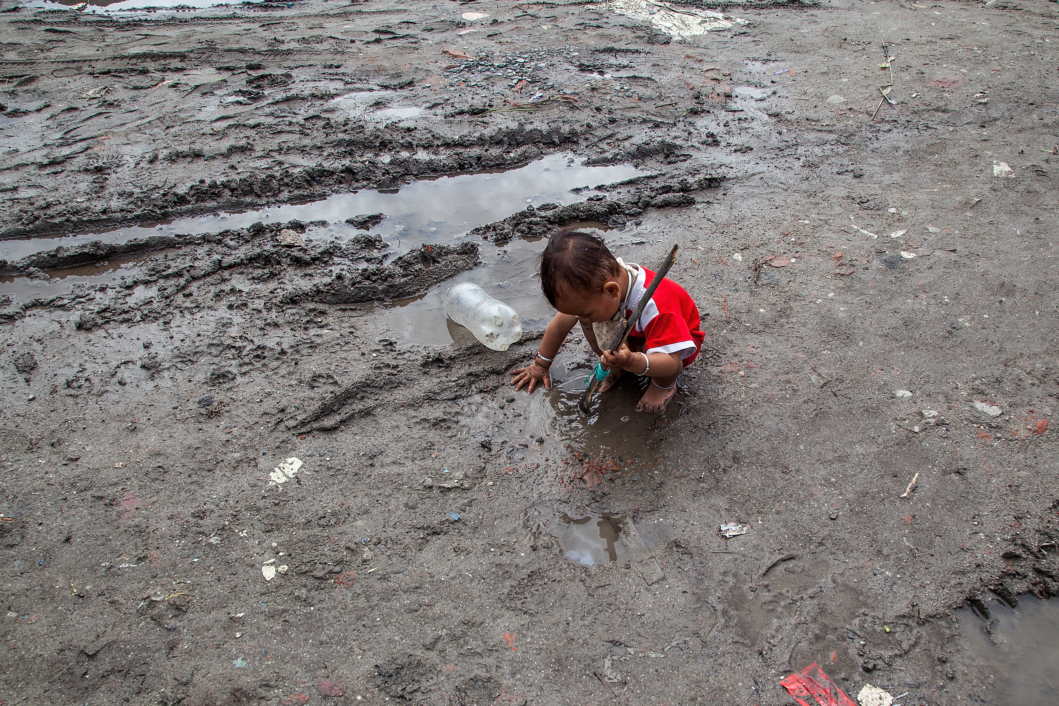 A young boy plays in the mud in a flooded lane inside the Chuchepati displacement camp on August 13, 2015, in Kathmandu, Nepal.
