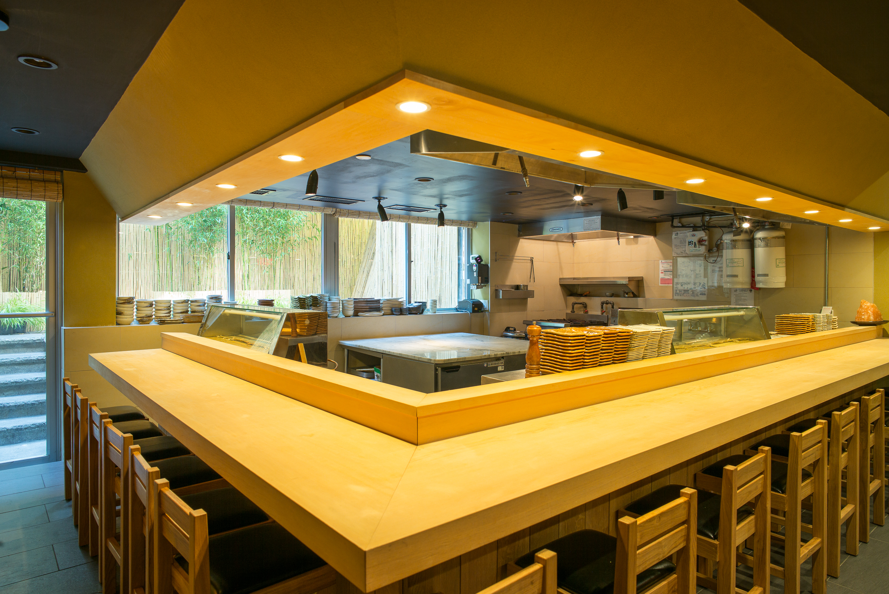 A chef’s counter with stools under a warm lighting. 