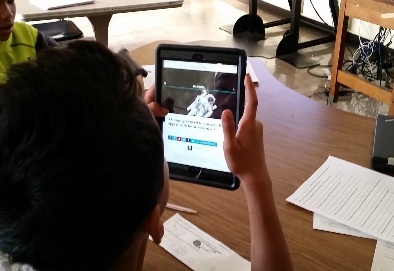 A student uses an iPad to learn about space