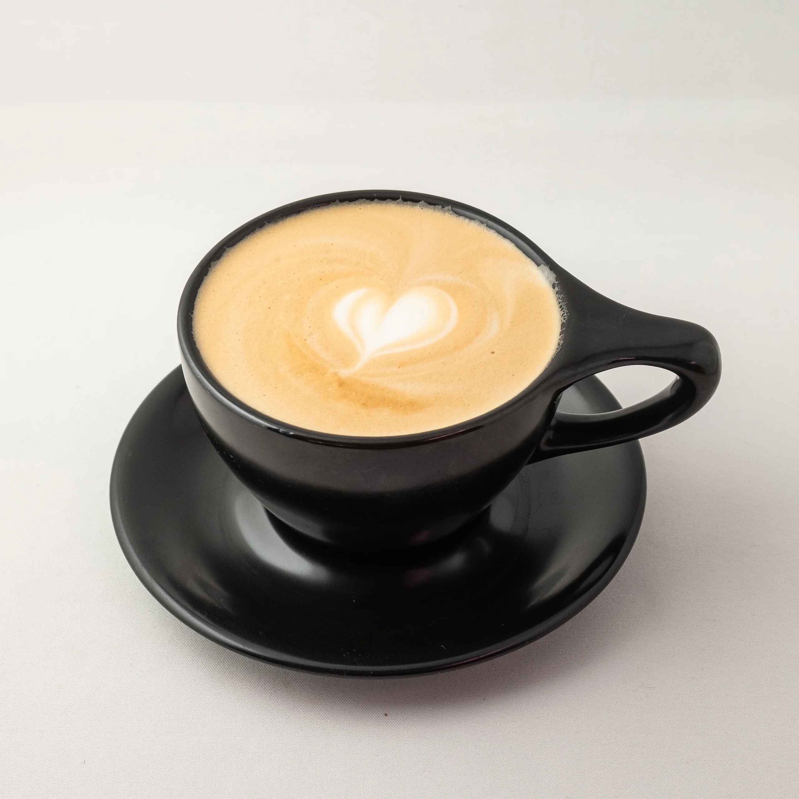 A latte in a black mug.