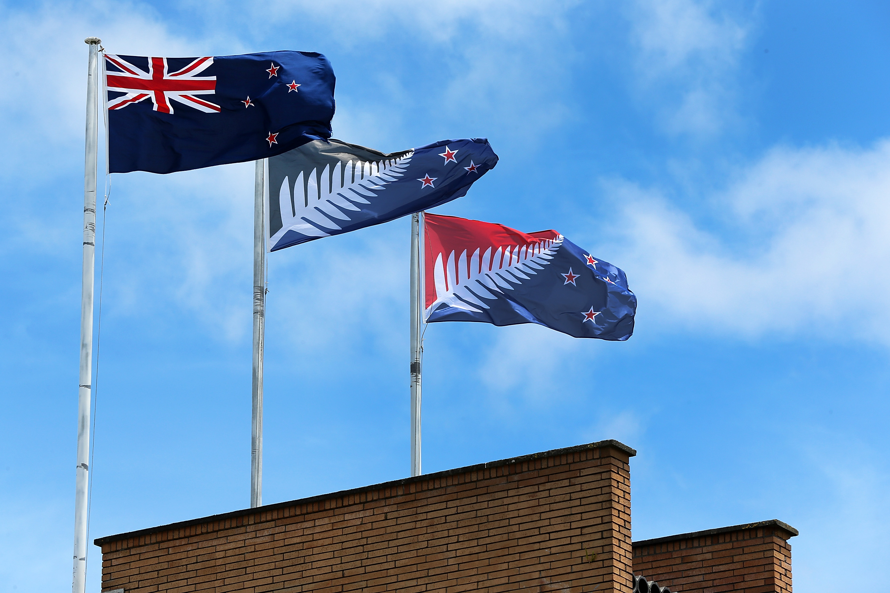 The current New Zealand flag (L), the referendum-winning blue-and-black Kyle Lockwood–designed flag (C), and the second-place red-and-blue flag (R) fly on a building in New Lynn, Auckland, on December 14, 2015, in Auckland, New Zealand.