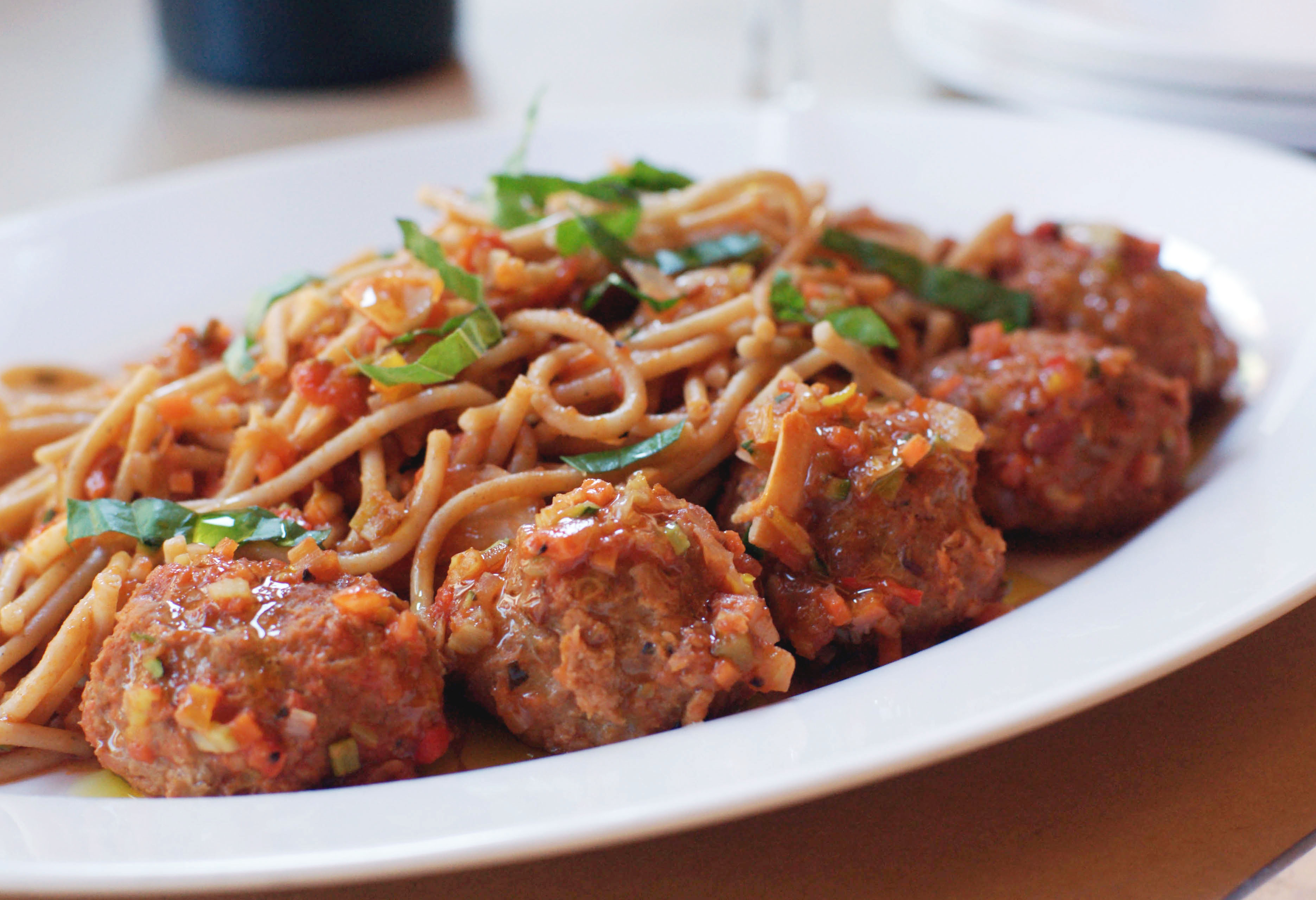 a plate of spaghetti and meatballs with a fork twirled inside the noodles 