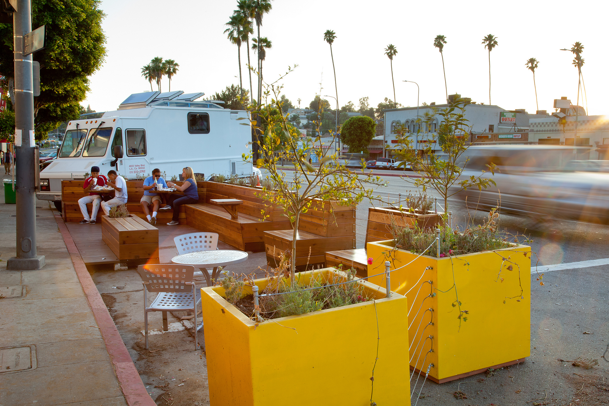 A wooden parklet with planters near a food truck in Los Angeles.