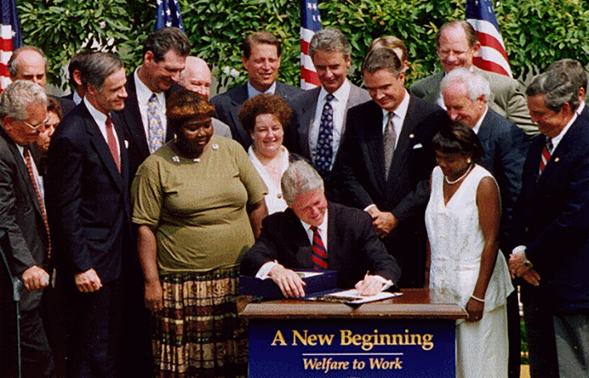 Lillie Harden stands alongside President Bill Clinton as he signs welfare reform into law.