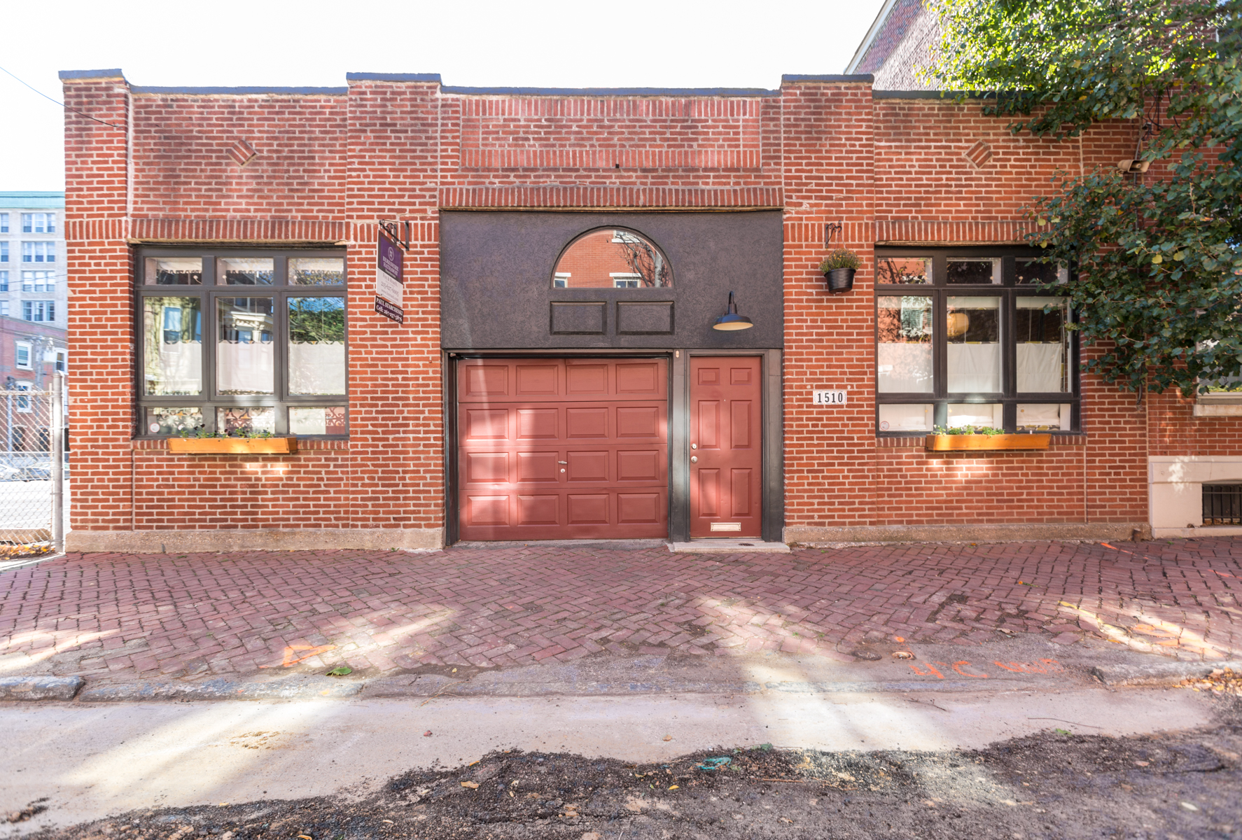 A one-story brick property with a red garage door in the center sandwiched by two windows.