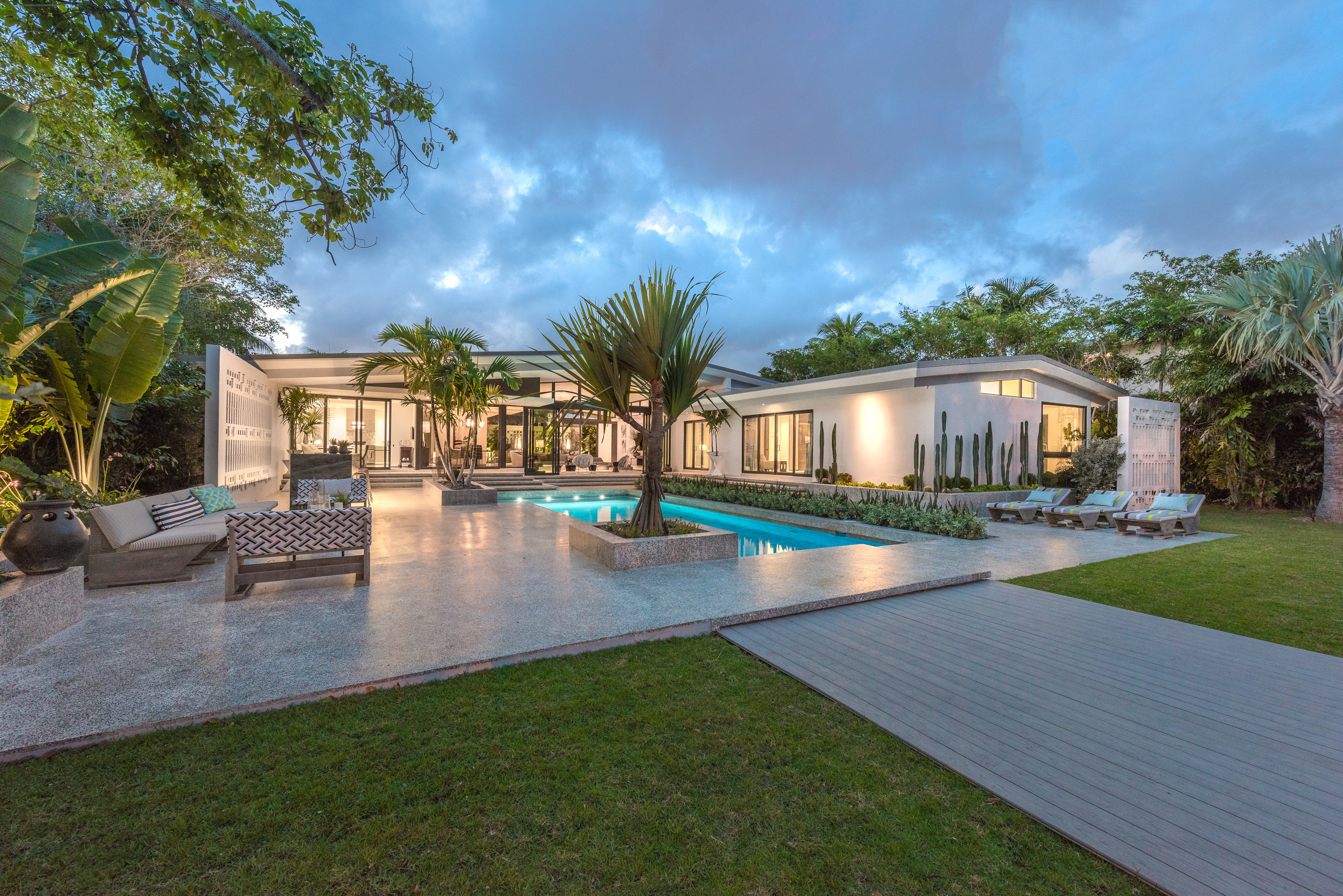 Backyard view of a midcentury modern home in Miami Beach designed by a famous french architect, with large glass windows.