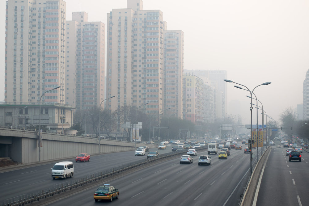 View of highway and high-rises in background with a blanket of smog hazing over the scenery. 