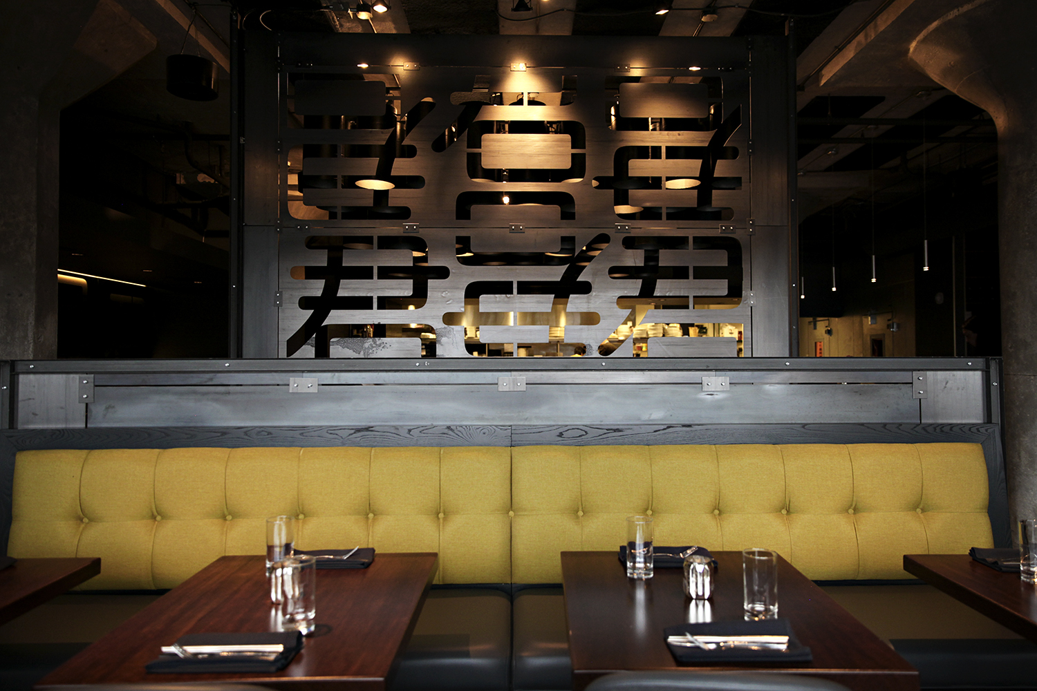 A plexiglass piece with Chinese characters hangs behind a gold-backed booth and a set table.