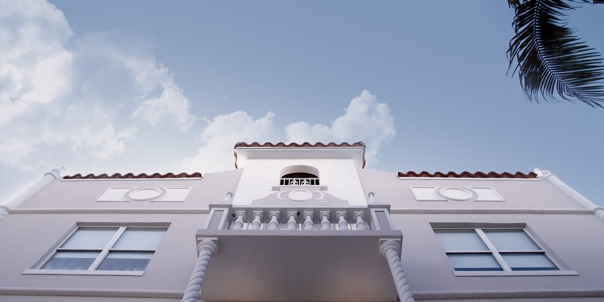 A street-level photo looking up at a new spanish-style hotel in south beach