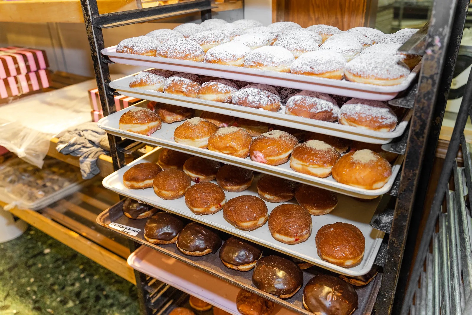 A bakery cart filled with trays of paczki. 