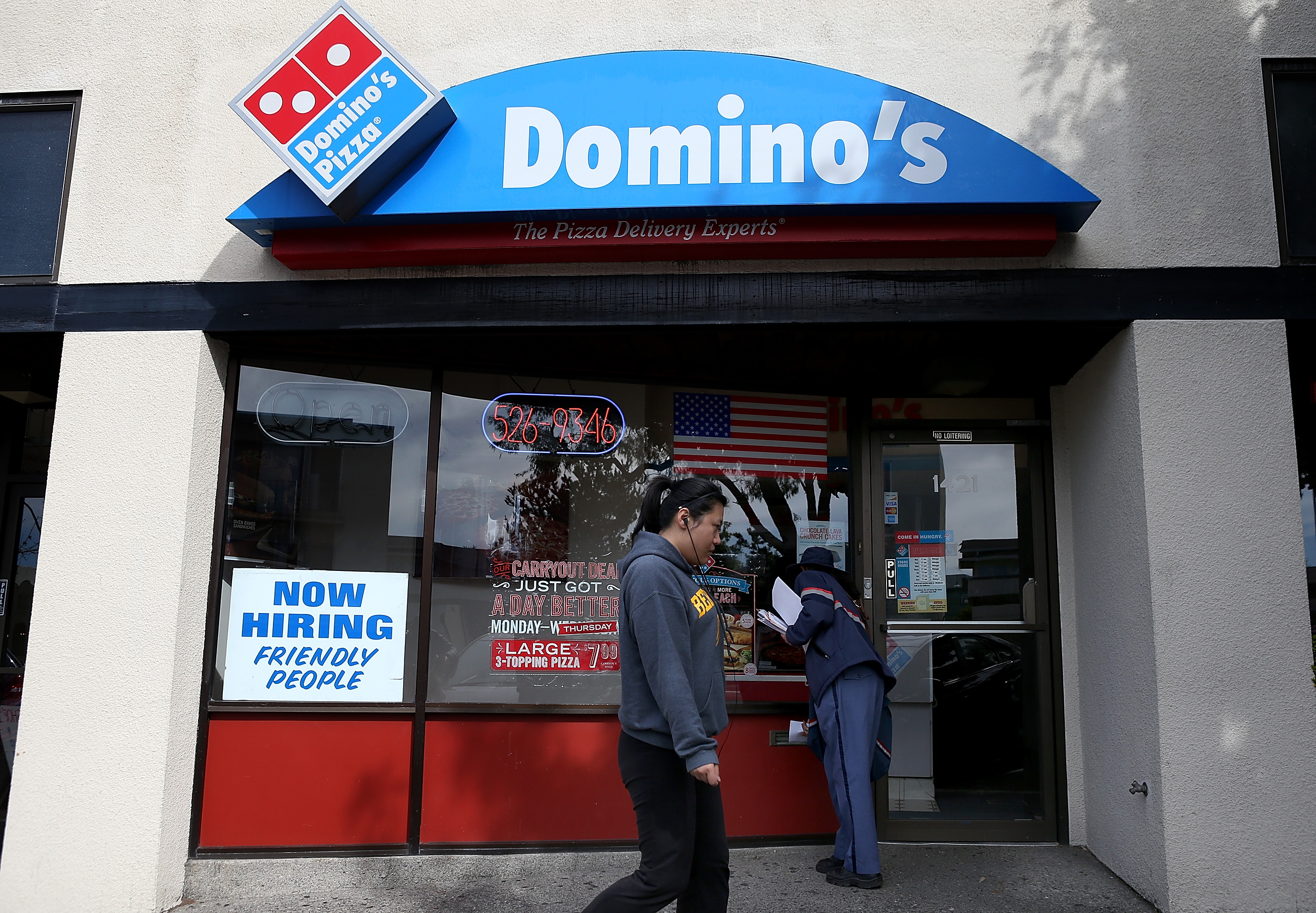 A person walks by the facade of a Domino’s Pizza restaurant