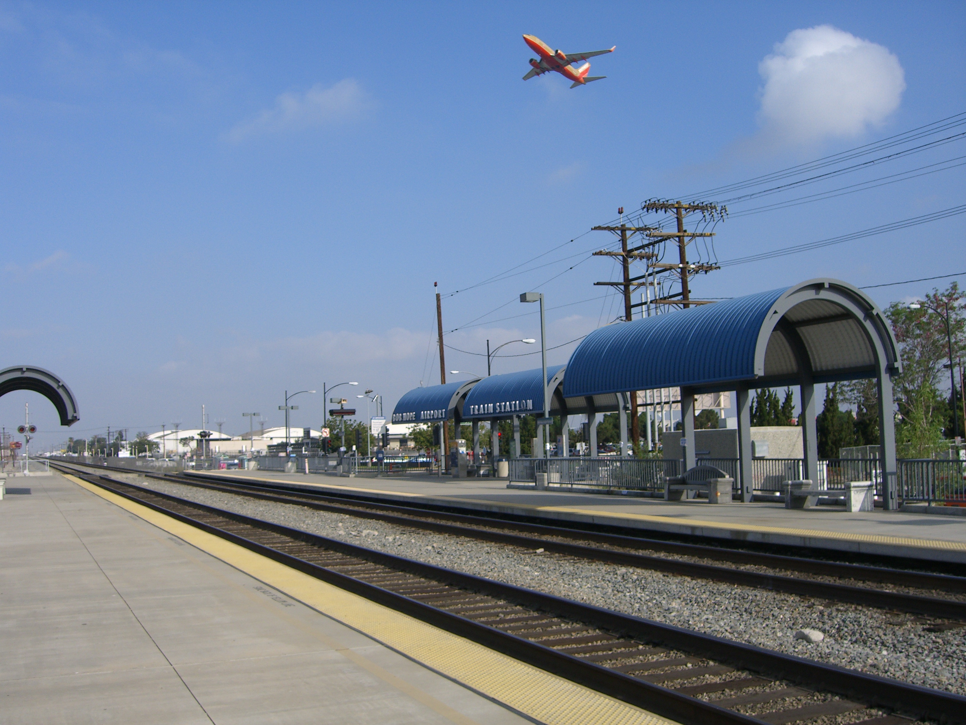 A plane flying over the Burbank Airport train station. 