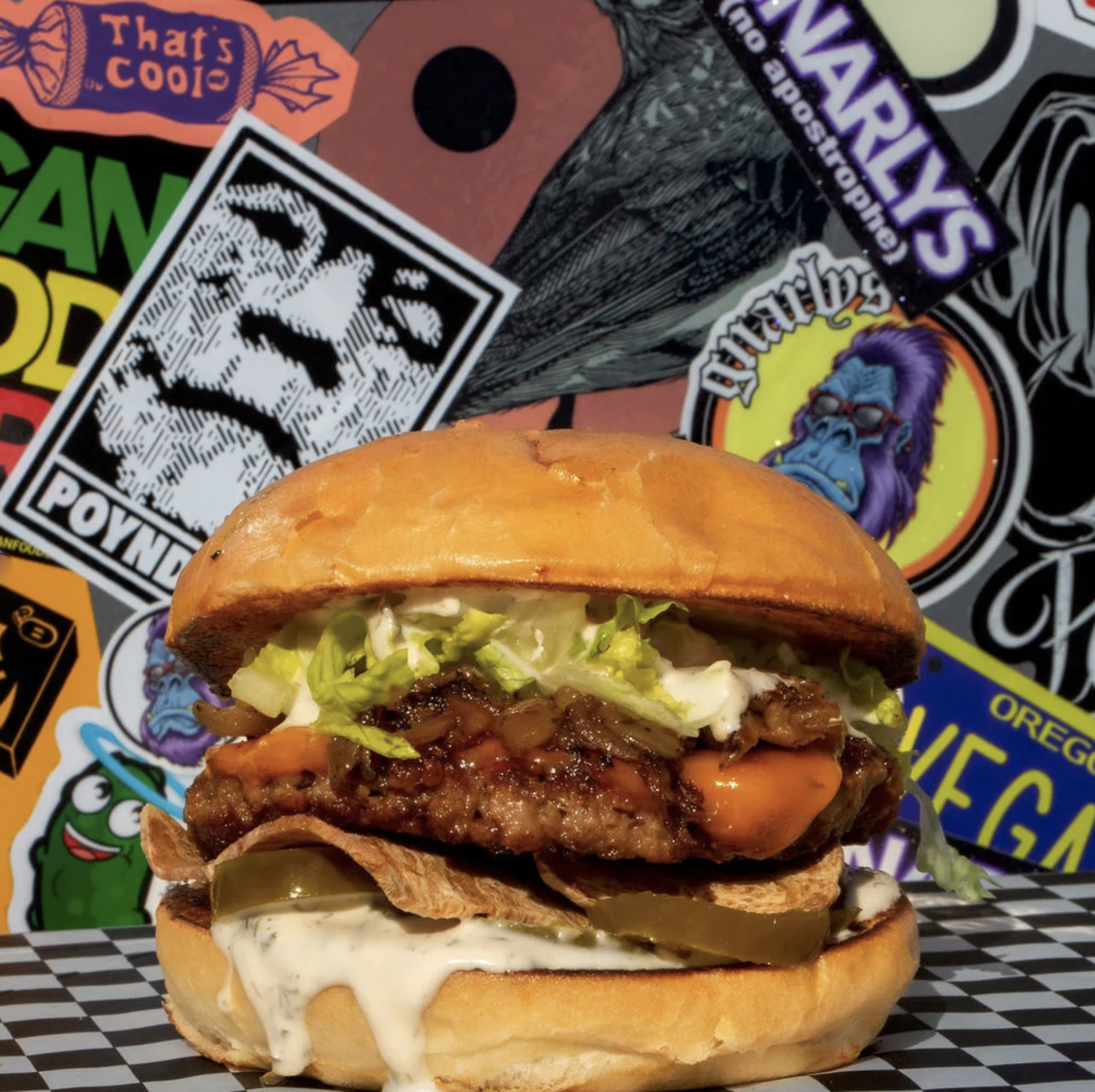 A photo of the Newport Nightmare vegan burger from Gnarlys food cart against a background covered in stickers