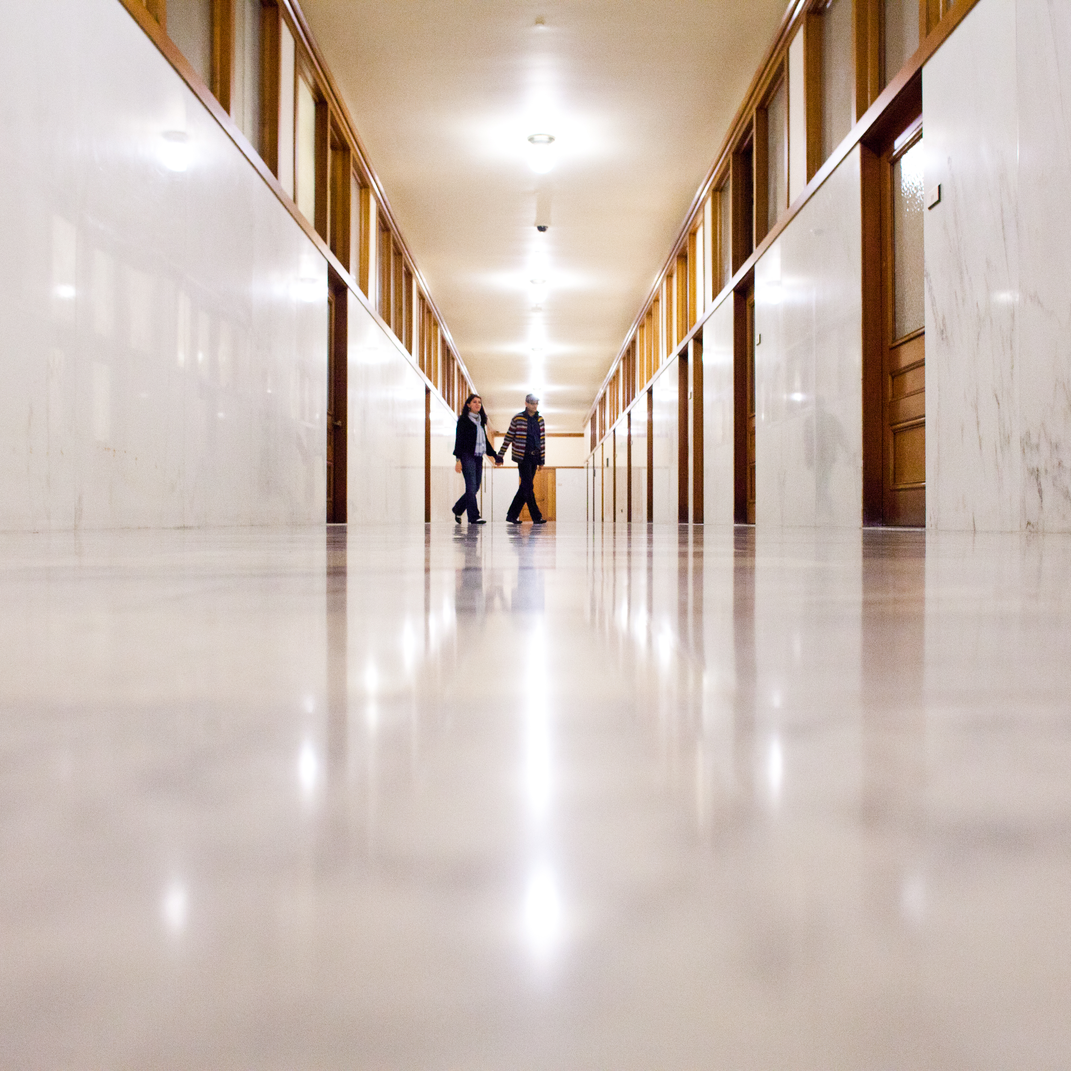 Inside San Francisco city hall, shot of a hallway with people walking down it. 