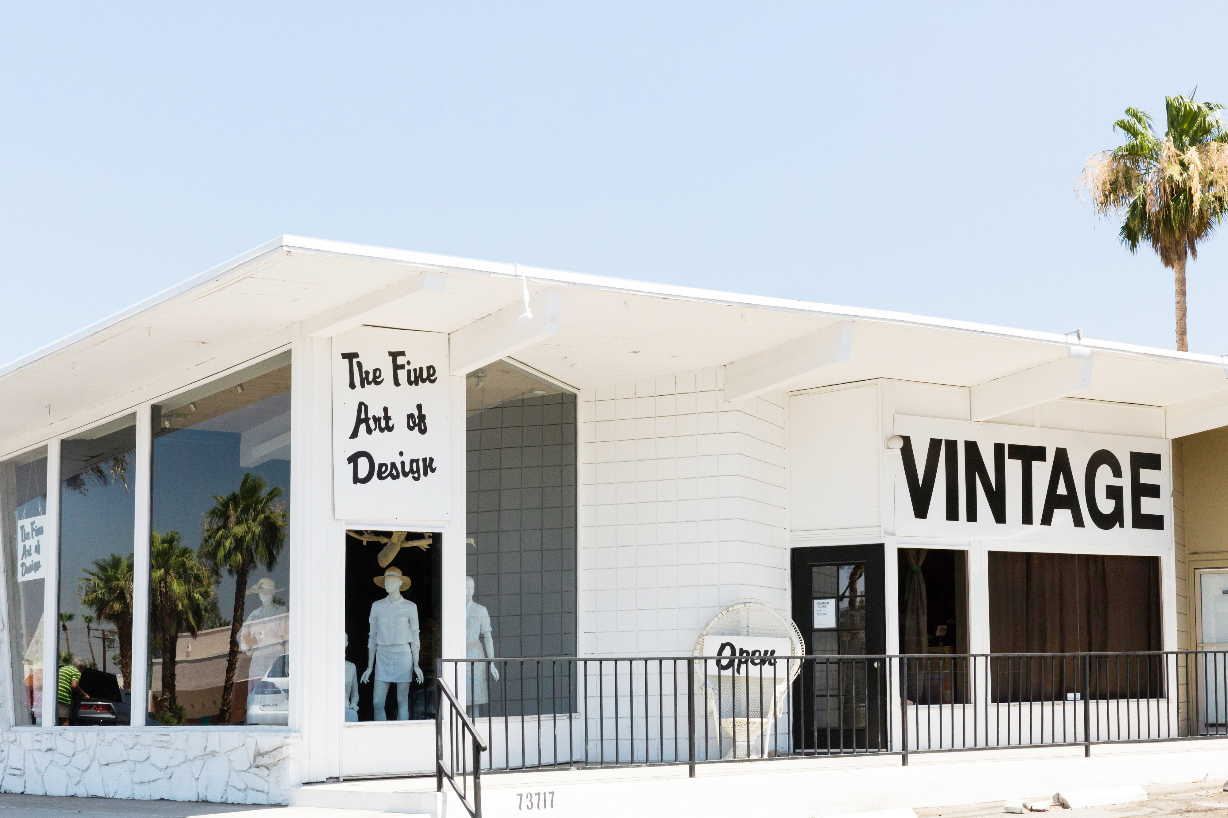 A vintage store in palm springs with a bright blue sky and palm tree in the background.