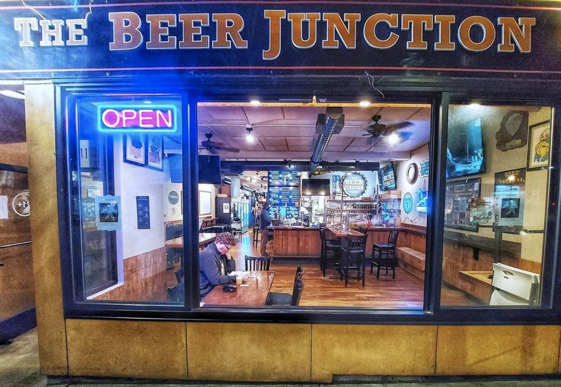 The front of the Beer Junction in West Seattle, with a lighted neon sign that says “open”