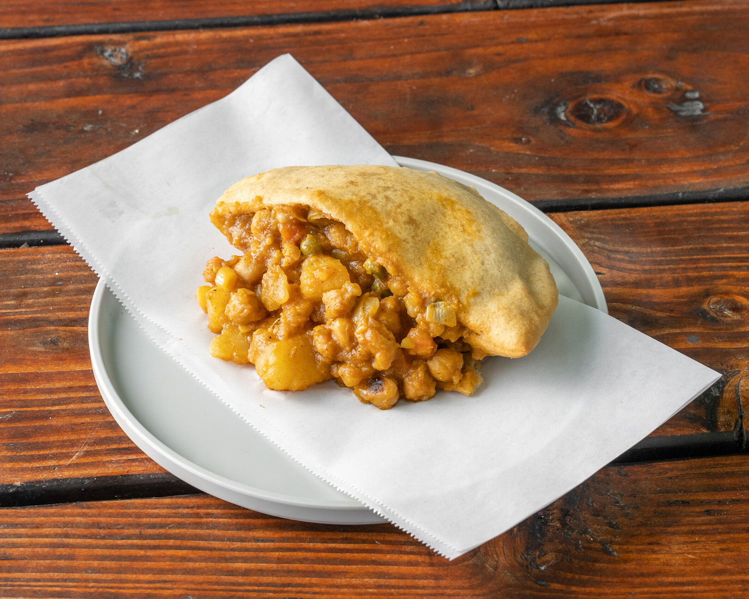 A photo of a vegan bake stuffed with chana aloo curry from Bake on the Run food cart