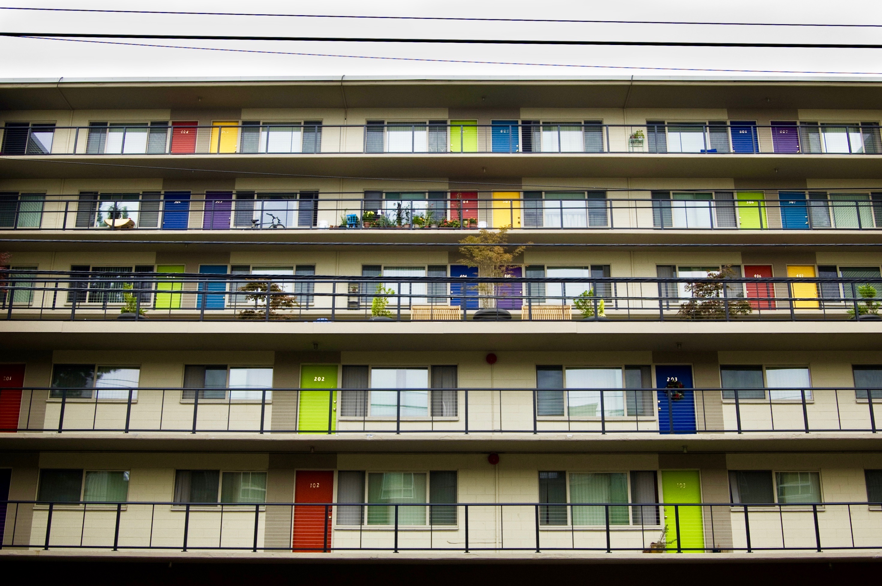 An apartment building with outside entrances to the units and colorful doors—red, yellow, green, blue, and purple.