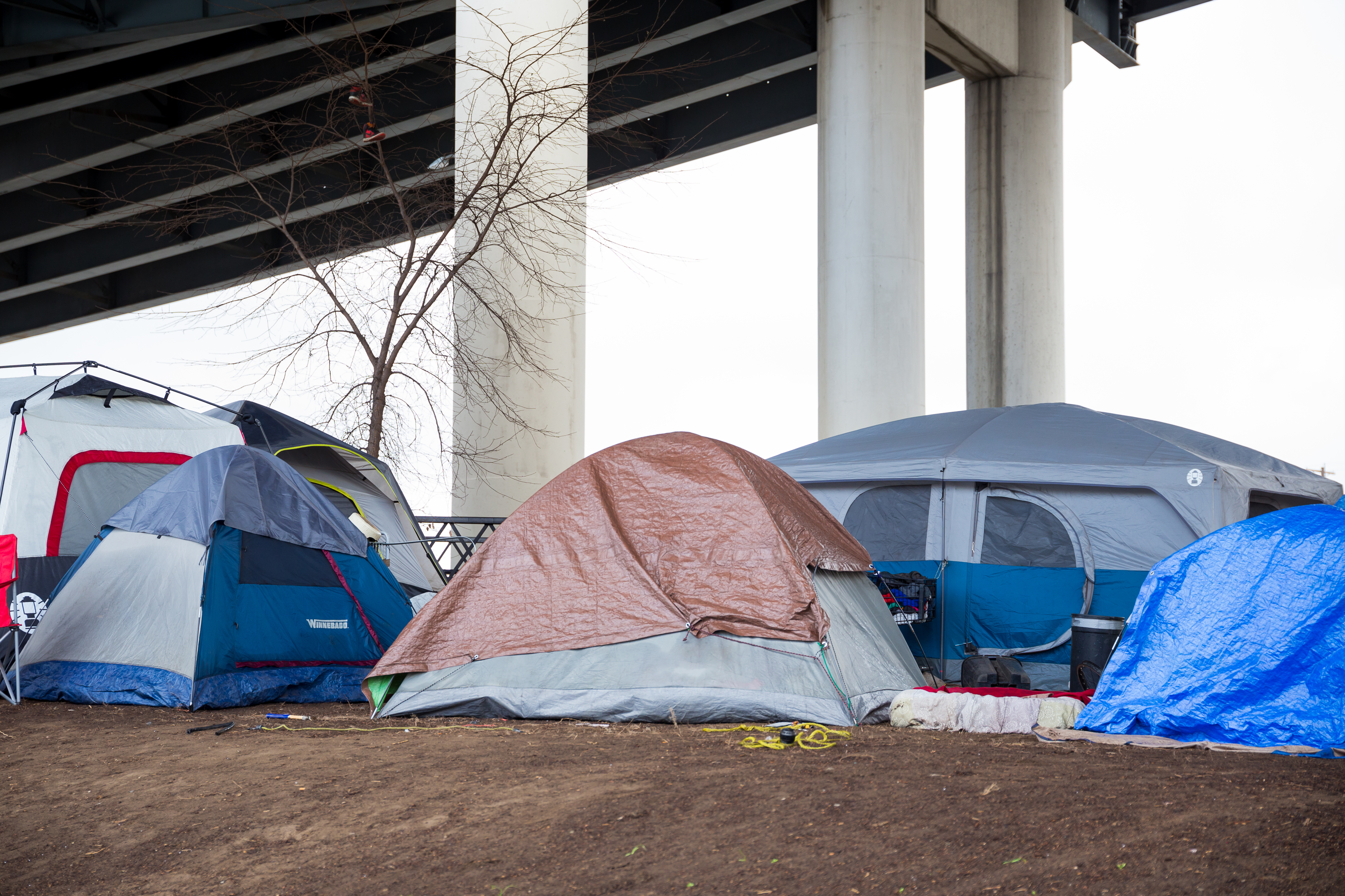 Several tents under a freeway overpass