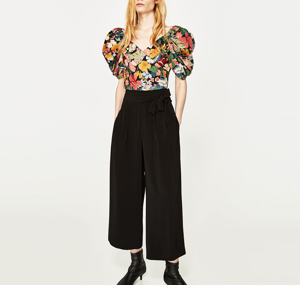 A model wearing black culottes and a floral blouse