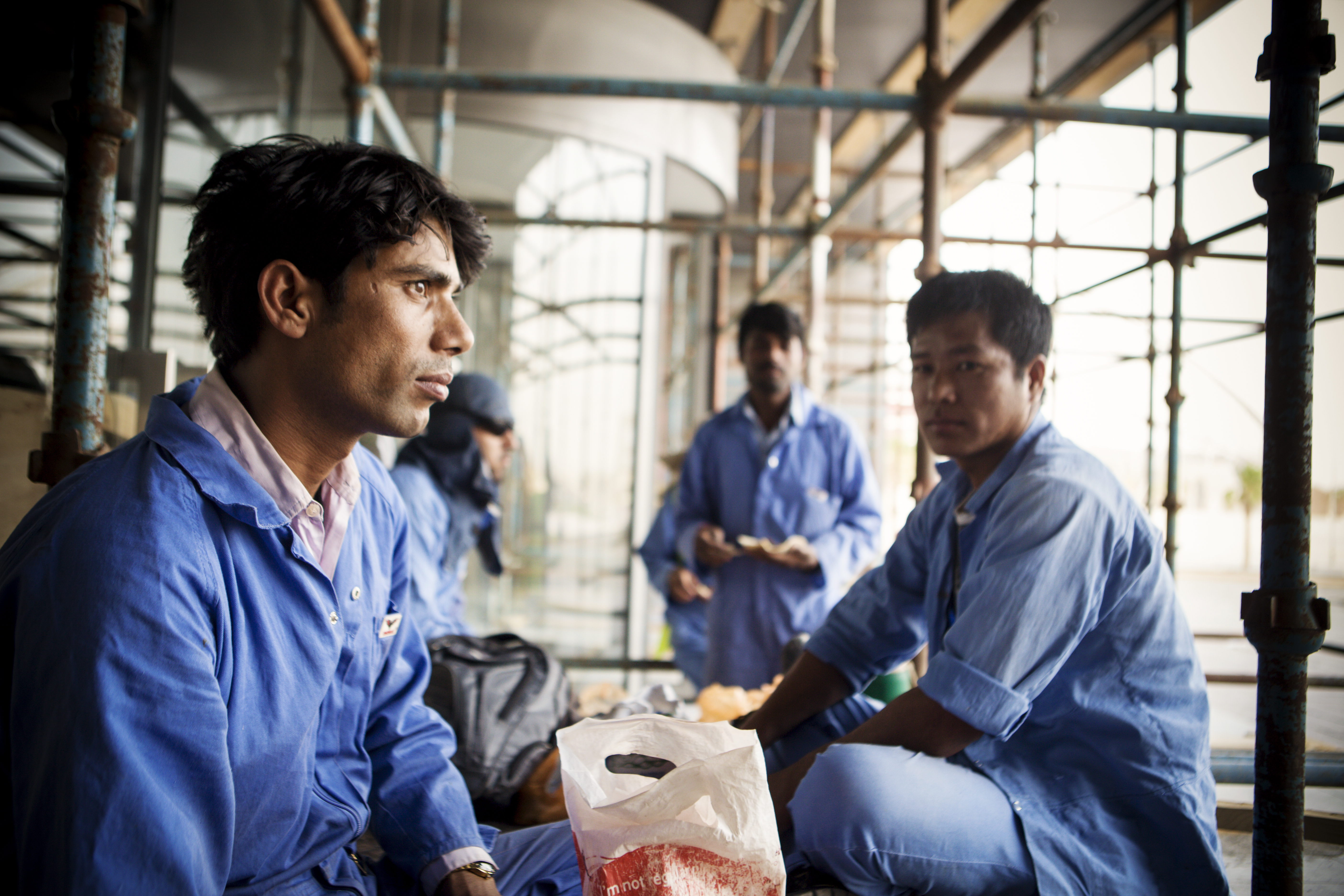 Migrant workers pause to eat at the Sports City area of Doha, Qatar