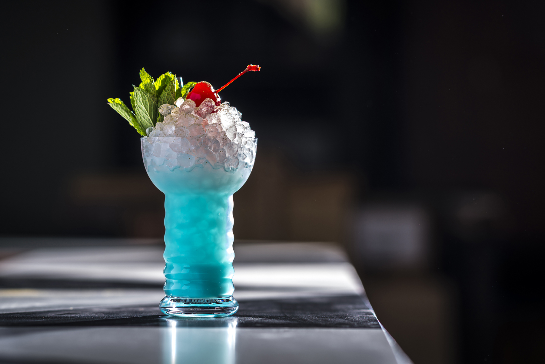 The Calpico Swizzle, a bright blue cocktail made with pebble ice.