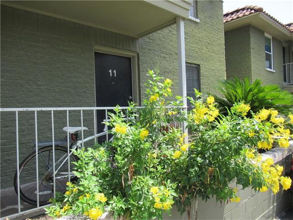 Dark green brick apartment building with yellow flowers in front