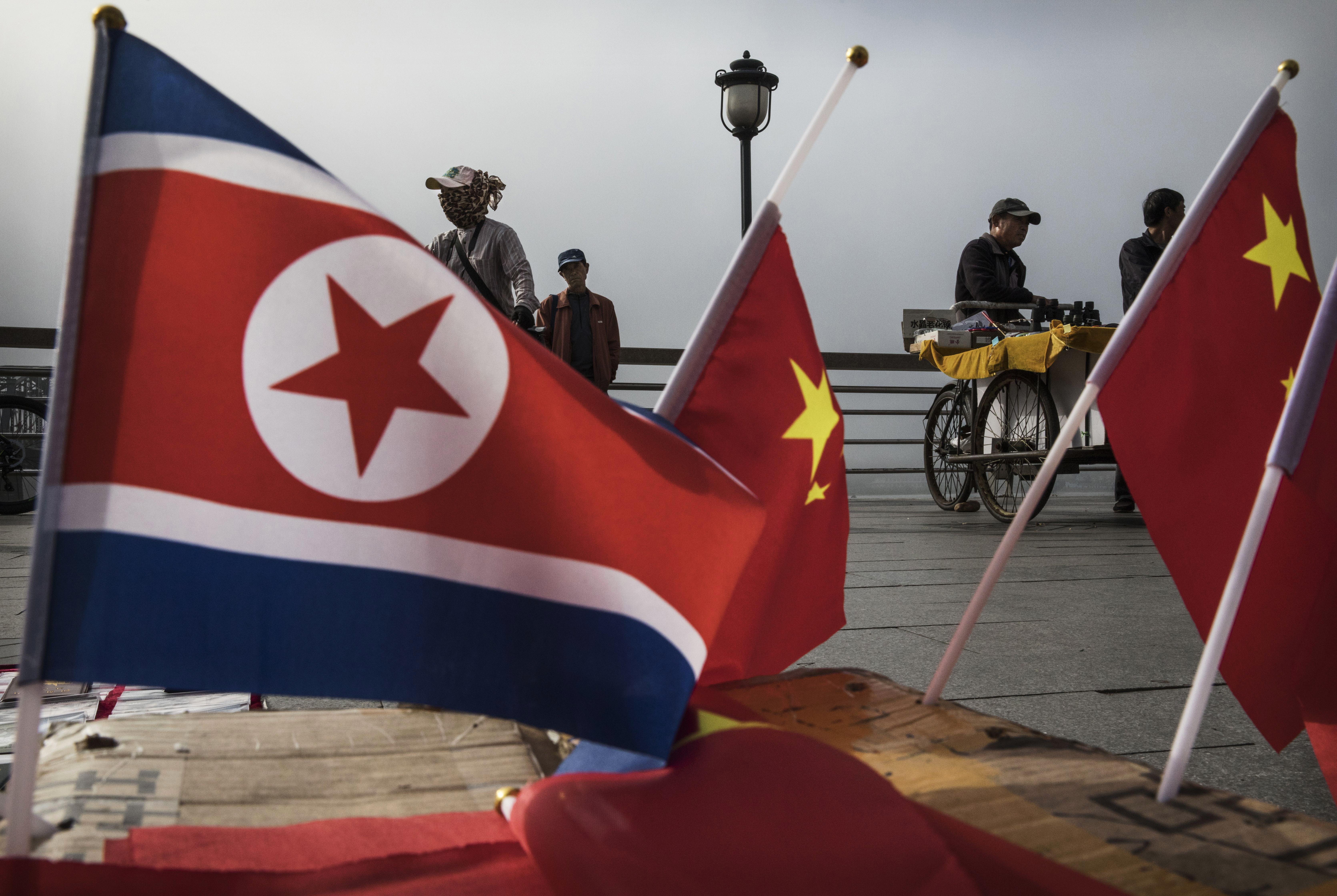 North Korean and Chinese flags on display on a boardwalk. 
