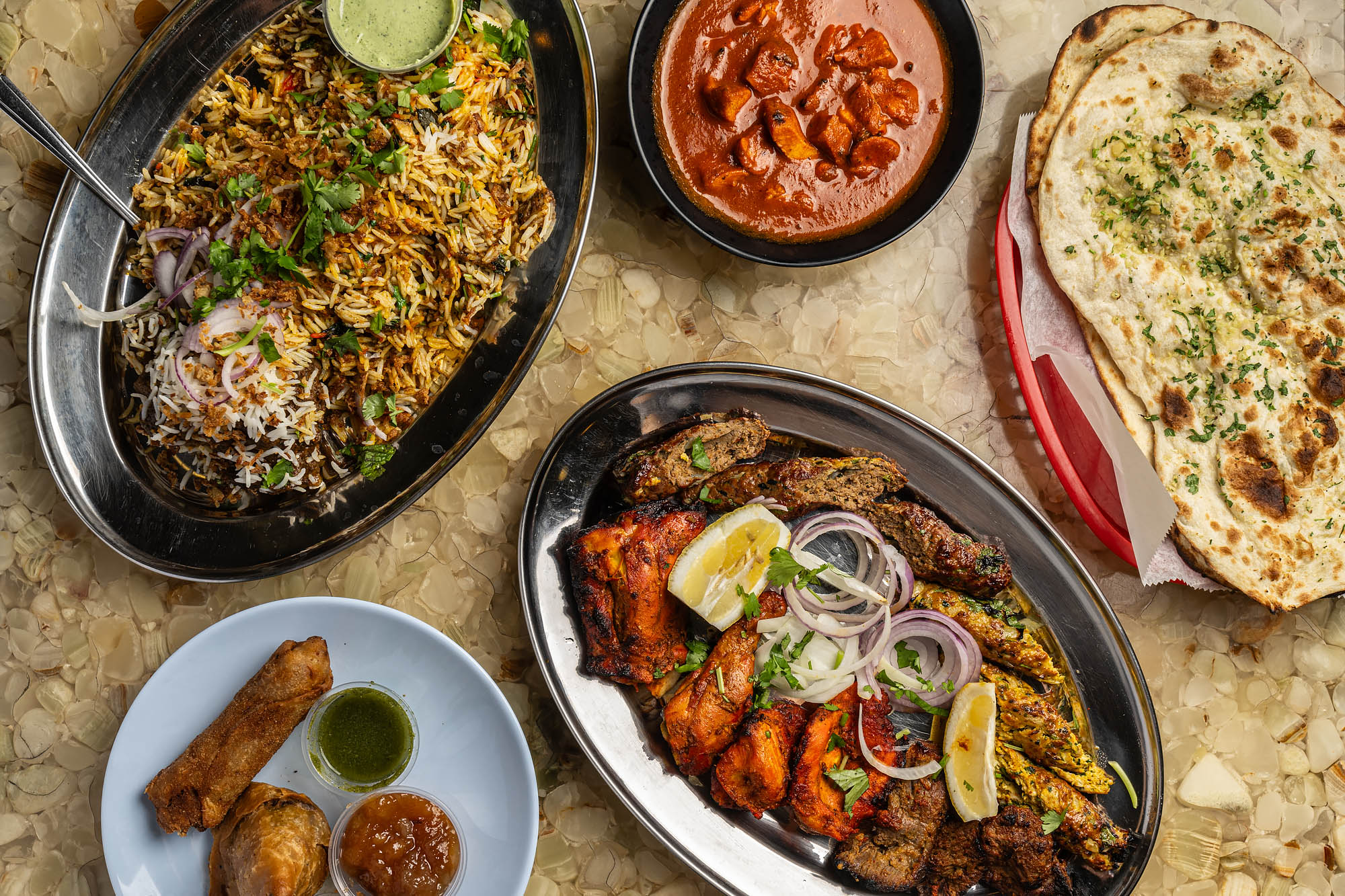 A selection of dishes — rice, kebabs, curries, naan — on a tabletop at Biriyani Kabob House.