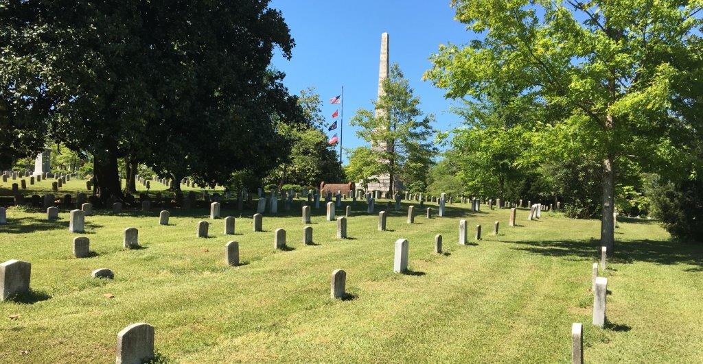A field of headstones, with a memorial obelisk beyond.
