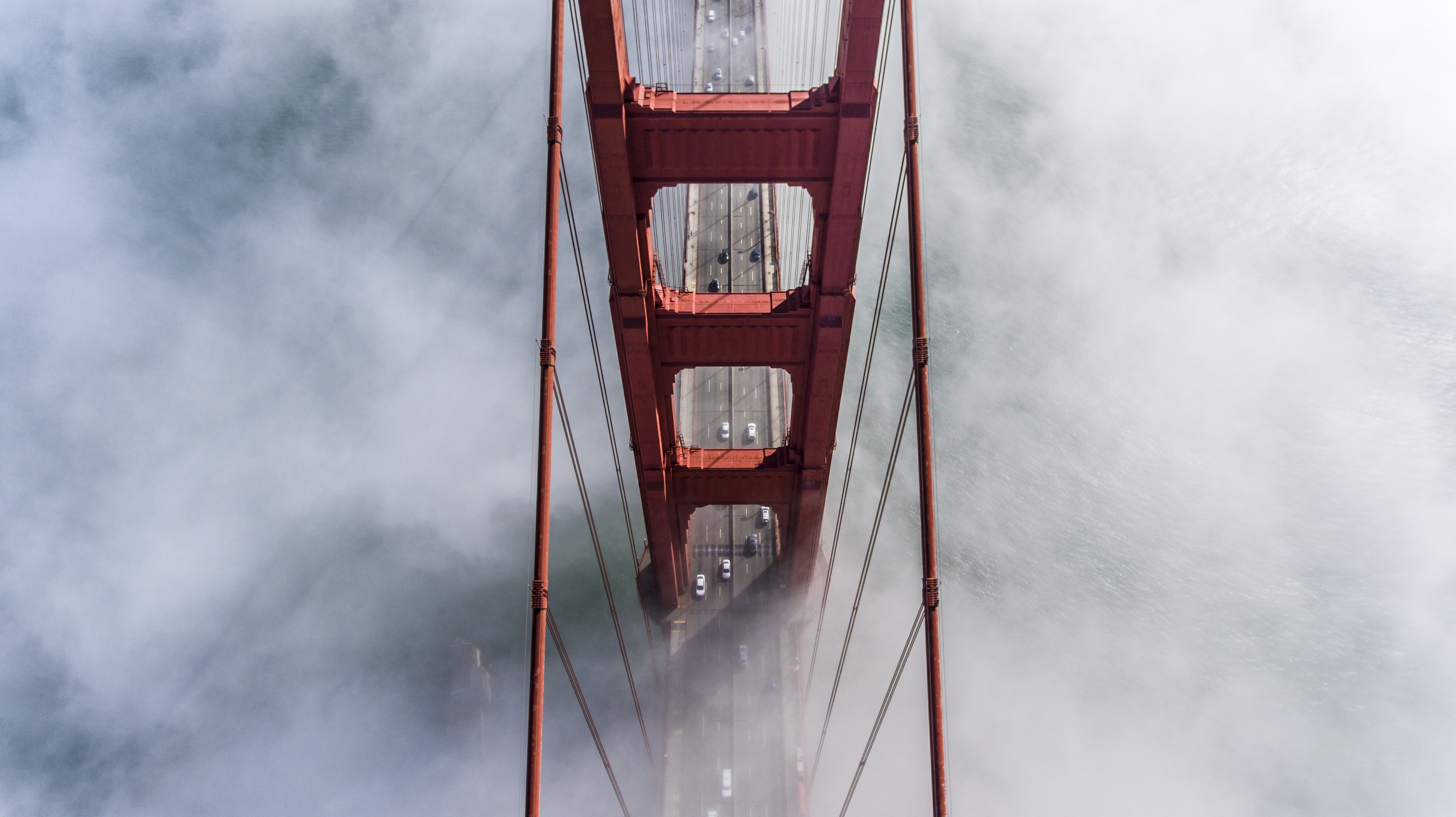 A photo from above one tower of the Golden Gate Bridge covered in fog.