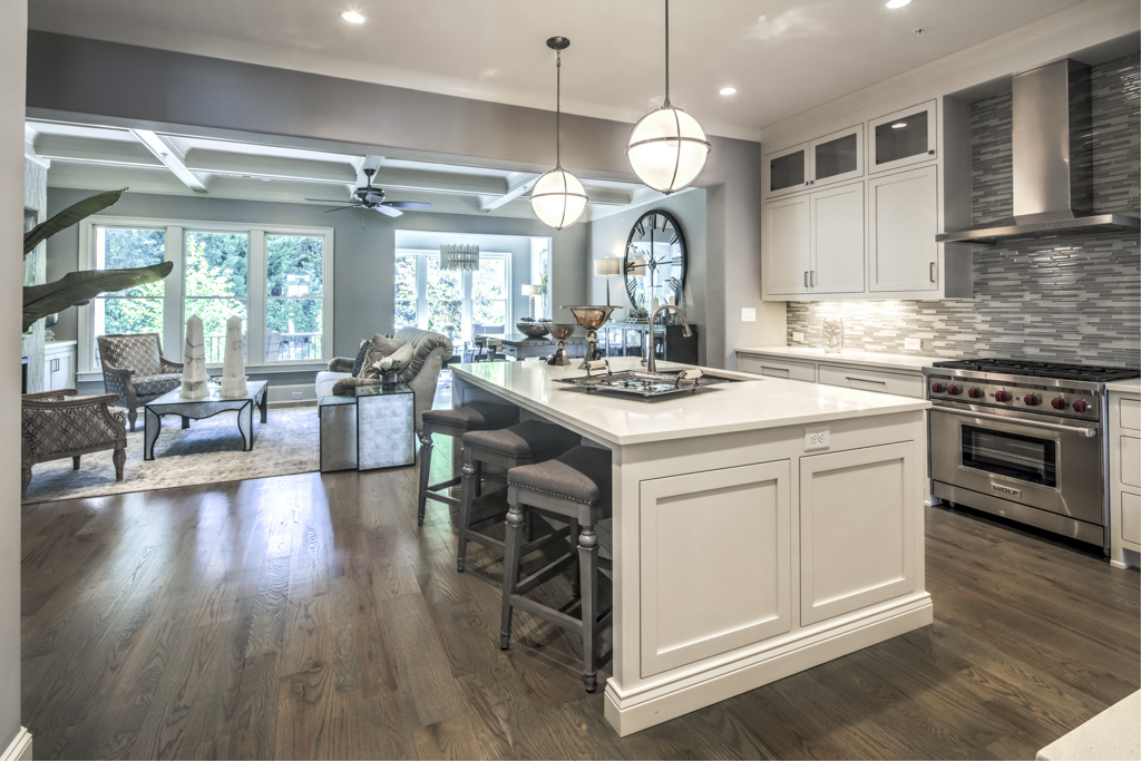A high-ceilinged kitchen with white cabinets and dark wood floors.