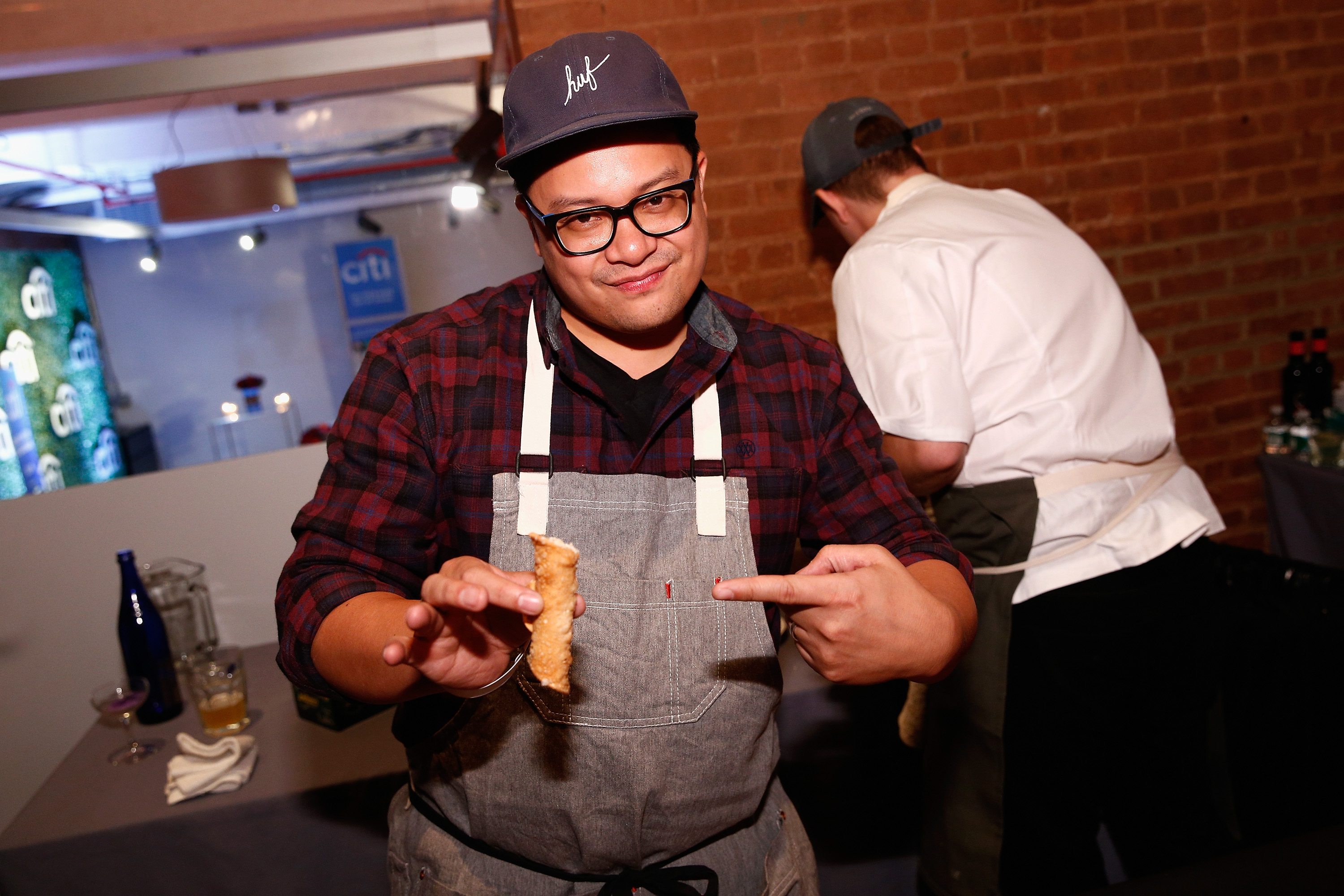 A man, chef Dale Talde, poses with an egg roll for a photograph.