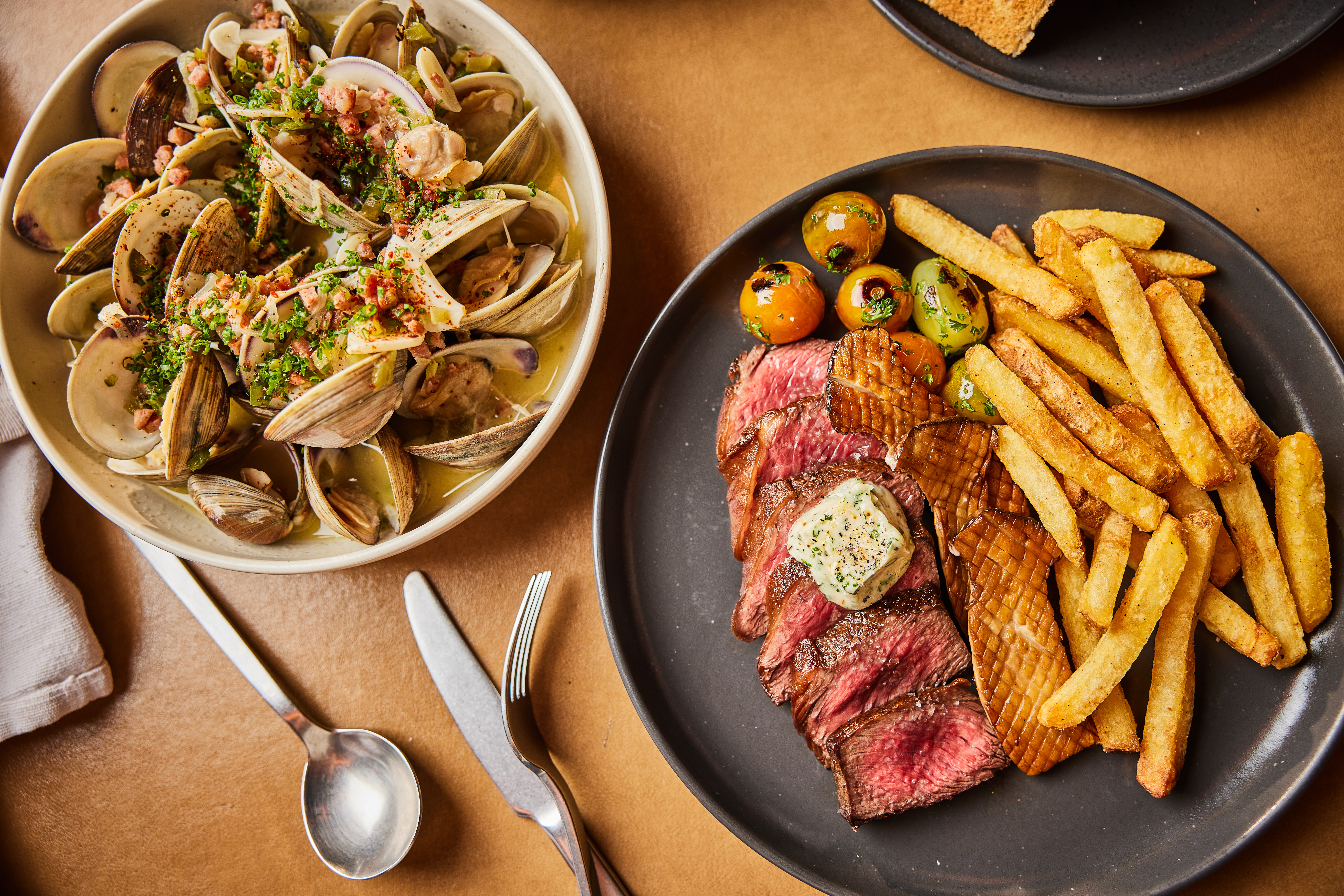 A plate of clams and a plate of steak and fries.