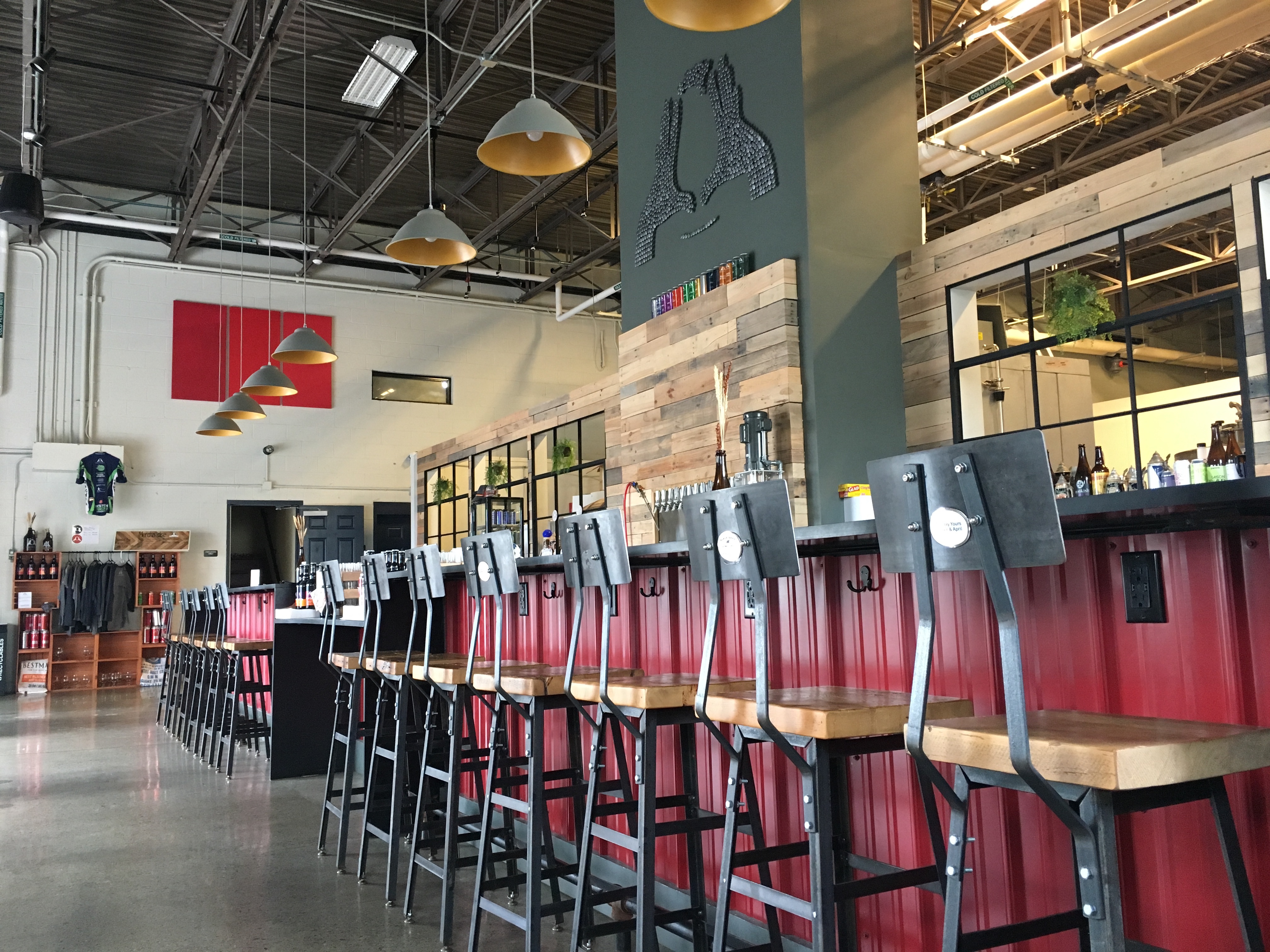 A low angle of barstools lined up against a red-based bar inside a brewery