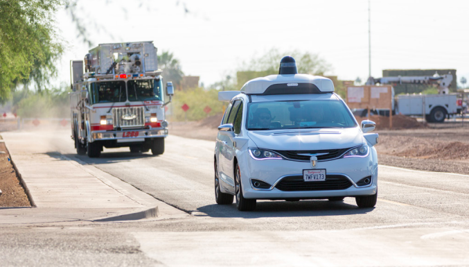 Waymo’s self-driving car driving ahead of a fire truck.