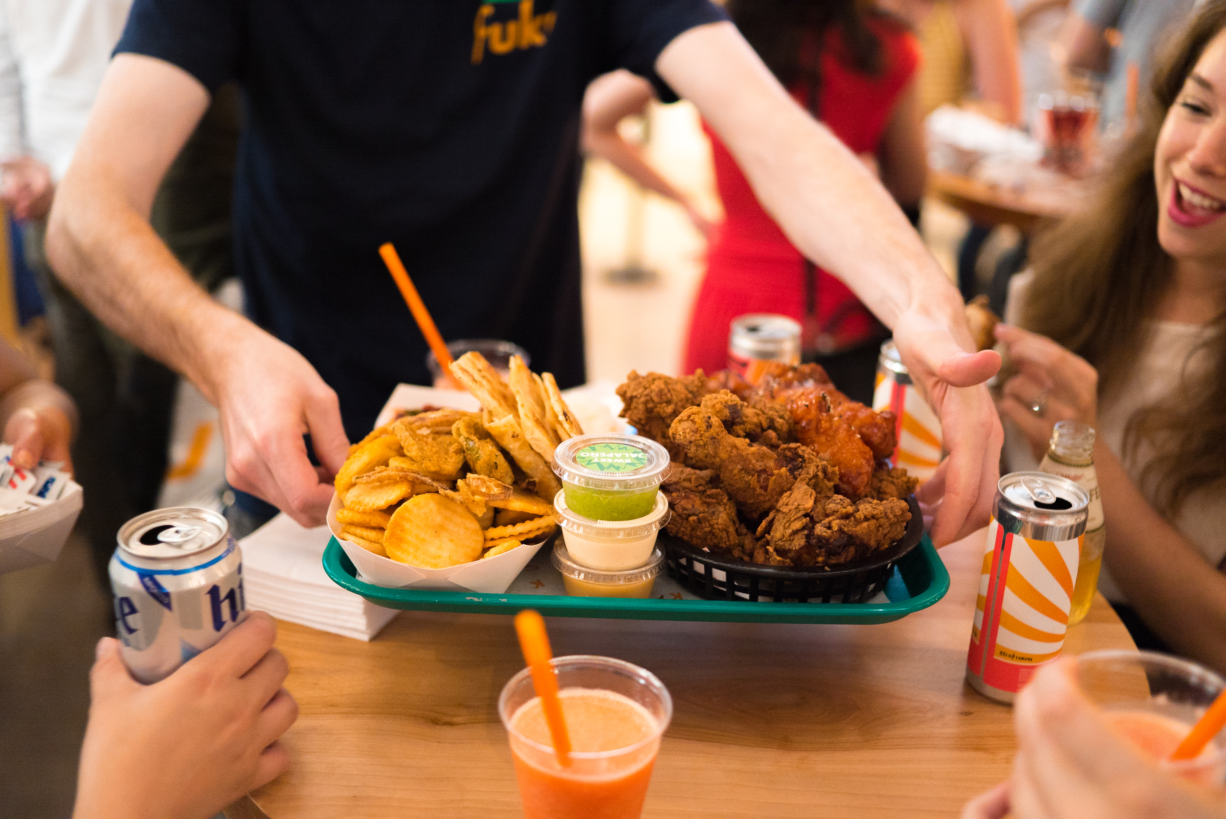 An employee at a restaurant carries a tray with fried chicken and sides.