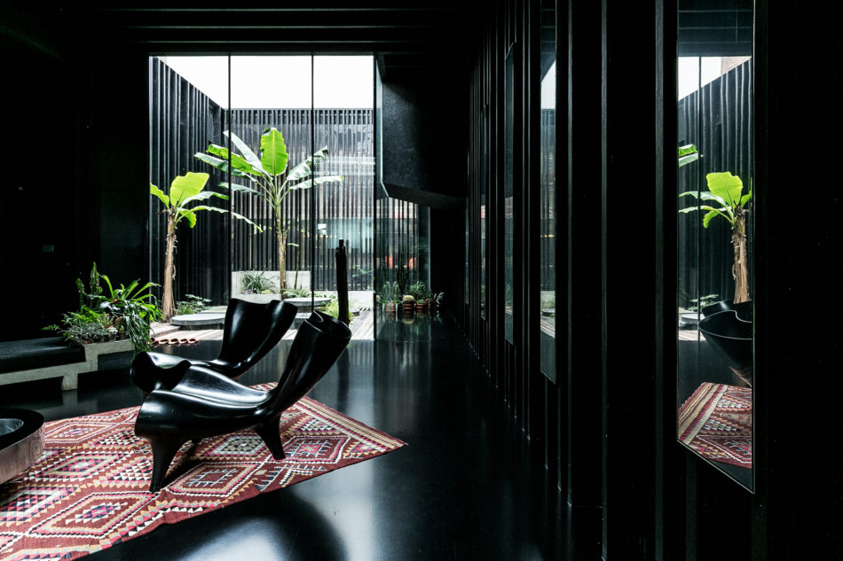 Interior shot of a living area painted completely black illuminated by a glazed courtyard. 
