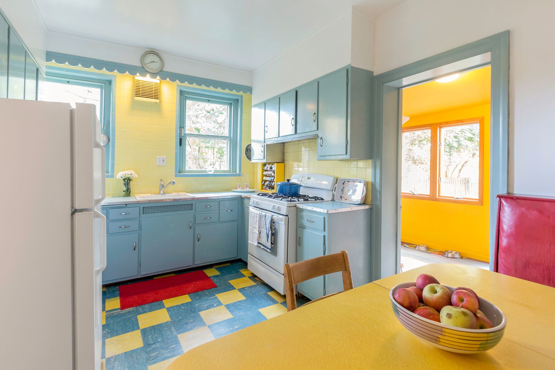 A colorful vintage kitchen with light blue cabinetry and yellow walls. 