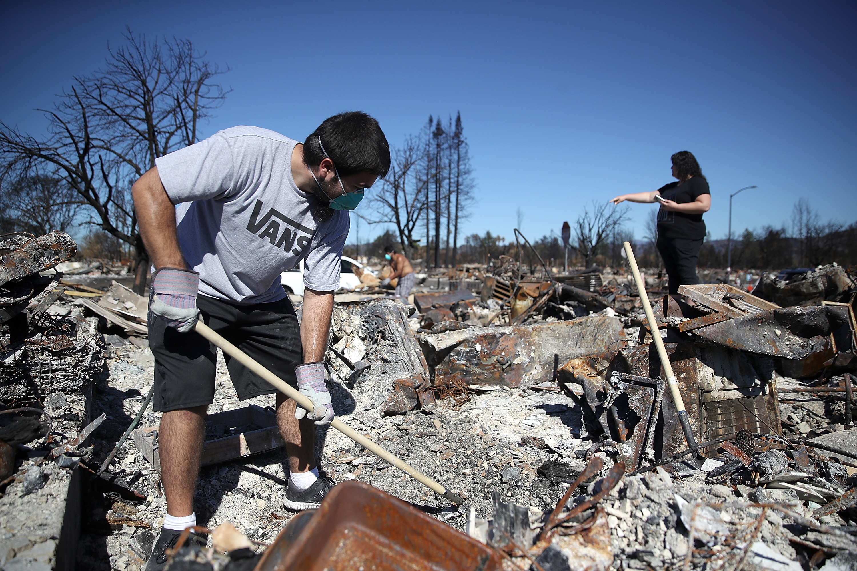 Ben Hernandez Jr. (L) sifts through the remains of his Coffey Park home.