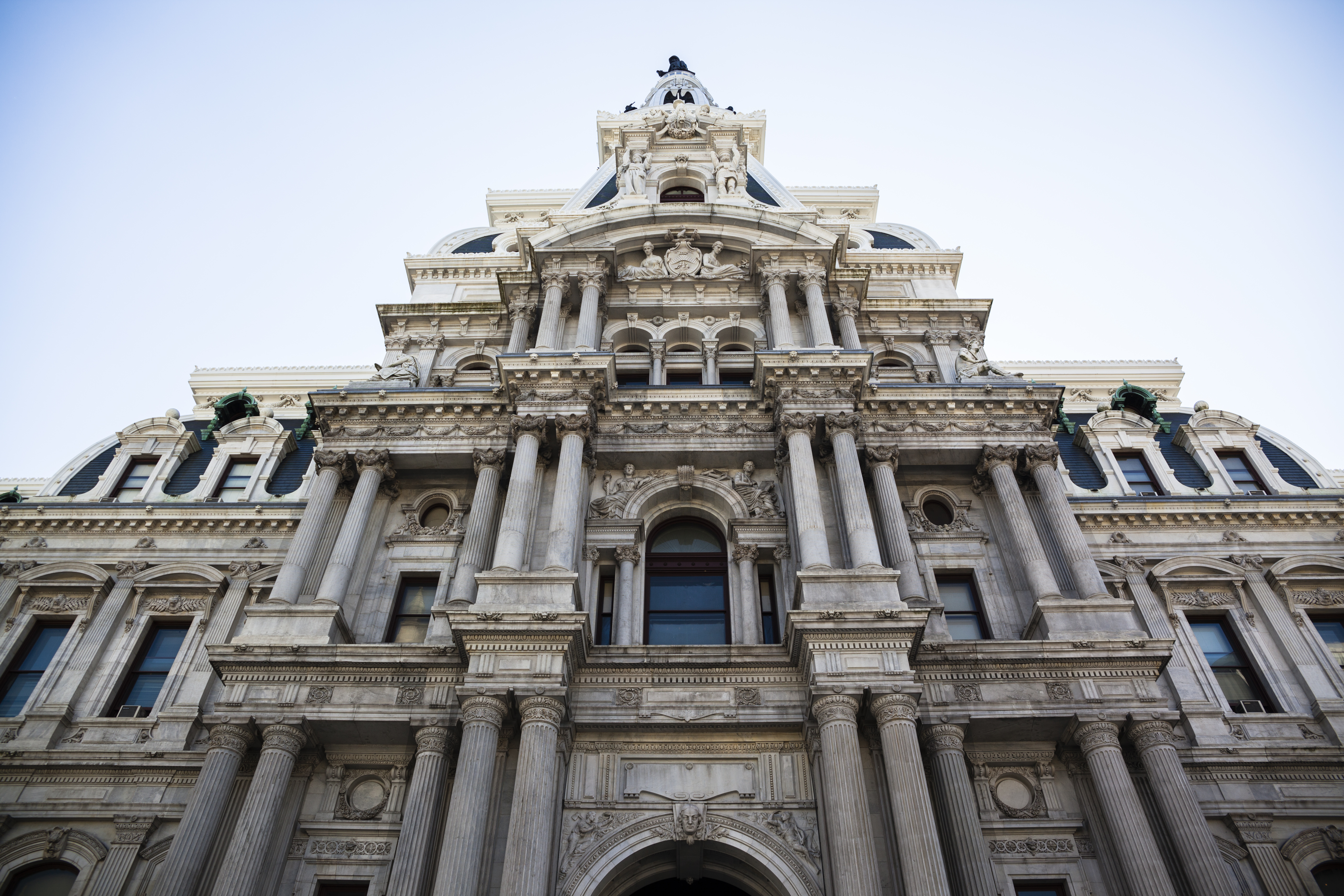 The exterior of Philadelphia City Hall. The facade is elaborately decorated with multiple columns and windows.