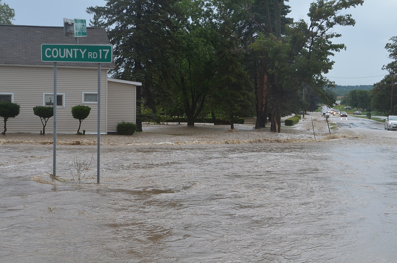 Flood waters slowing rising beneath a roadside sign.
