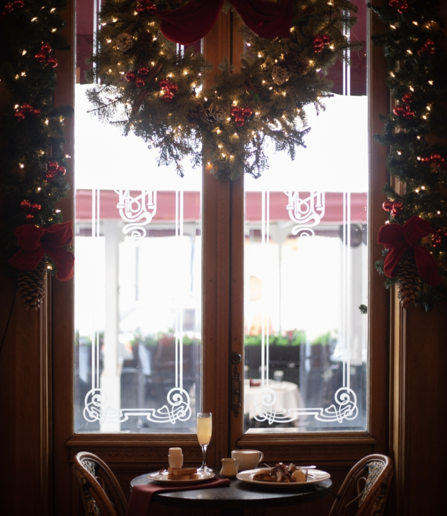 A holiday decorated window frame with a meal in front of it.
